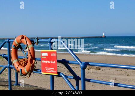 Un anneau de sauvetage attaché à des rampes bleues sur fond d'une plage déserte. Banque D'Images