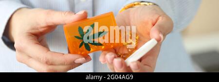 Les mains des femmes tiennent le pot de pilules de marijuana Banque D'Images