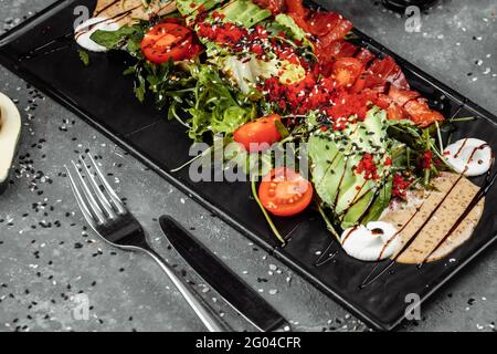 Salade de saumon gravlax. Salade de saumon fumé, avec légumes variés tomates cerises avocat olives noires carottes pousses concombres et lime. Délicieux en bonne santé Banque D'Images