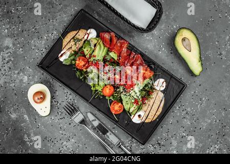 Salade de saumon gravlax. Salade de saumon fumé, avec légumes variés tomates cerises avocat olives noires carottes pousses concombres et lime. Délicieux en bonne santé Banque D'Images