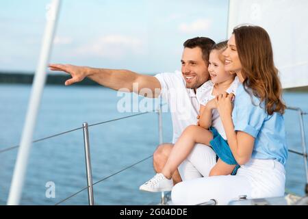 Parents et fille qui s'embrasent debout sur la terrasse du bateau en regardant de côté Banque D'Images