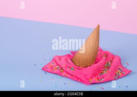 Idée créative minimale faite de cône de crème glacée et de chiffon déversé sur fond bleu pastel et rose. Concept minimaliste d'été de la nourriture et de cycle Banque D'Images