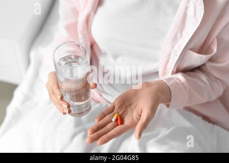 Belle jeune femme prenant des pilules dans la chambre, gros plan Banque D'Images