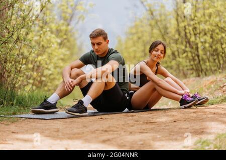 Faire reposer l'homme et la femme après un entraînement physique à l'extérieur. Banque D'Images