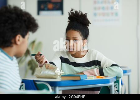 Portrait d'une adolescente afro-américaine parlant à un ami dans une salle de classe scolaire, espace de copie Banque D'Images