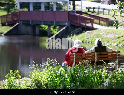 Deux amis assis sur un banc de parc Banque D'Images