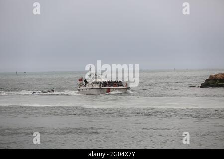 Le navire de la Garde côtière tunisienne entre dans le port du district après avoir sauvé des dizaines d'immigrants illégaux et remorqué derrière le bateau qu'ils étaient le 27 mai 2021 dans le district de la Garde nationale marine du Centre, Sfax, Tunisie. La Tunisie est devenue un lieu central pour les migrants qui tentent de traverser la Méditerranée pour atteindre l'Europe. Au cours des derniers mois, la Garde côtière tunisienne a arrêté des centaines de migrants illégaux en provenance de différents pays africains. Ils veulent quitter leur pays en raison de l'absence de possibilités d'emploi, surtout après la crise de la COVID-19. Mais le voyage est très dangereux et récemment Banque D'Images