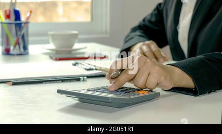 Gros plan des femmes utilisant des calculatrices et des prises de notes, des rapports comptables, des idées de calcul des coûts et des économies. Banque D'Images