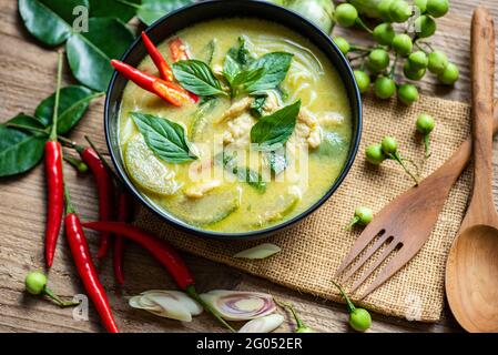 Poulet vert curry cuisine thaïlandaise sur un bol à soupe avec ingrédients herbes végétales et épices piment poivre sur fond de table en bois, curry vert traditionnel Banque D'Images