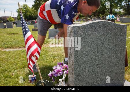 Grove, États-Unis. 31 mai 2021. Ray Pack ratis la tombe de son oncle John qui était membre de l'armée américaine, et qui a également enseigné à Pack comment chasser et pêcher. Ray Pack, 67 ans, de Grove City, visite plusieurs tombes de sa famille et de ses amis le jour du souvenir. Pack n'a jamais servi dans l'armée, mais lui et un ami ont signé ensemble. Pack n'était pas autorisé dans l'armée, mais l'ami avec qui il s'était inscrit était et plusieurs membres de sa famille immédiate étaient aussi des membres du service militaire, y compris son oncle, son frère et son père. Crédit : SOPA Images Limited/Alamy Live News Banque D'Images