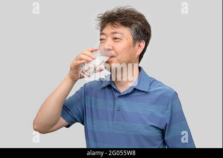Homme asiatique d'âge moyen tenant un verre d'eau. Banque D'Images