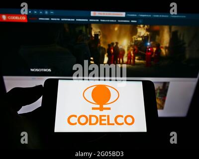 Personne tenant un téléphone mobile avec le logo d'entreprise de la société minière chilienne Codelco sur l'écran en face de la page Web. Mise au point sur l'affichage du téléphone. Banque D'Images