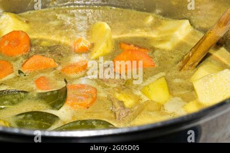 Ragoût de boeuf mijoter dans un pot sur une cuisinière, vue en angle bas. Feuilles de Laurier visibles avec un mélange de légumes et une cuillère en bois. Banque D'Images