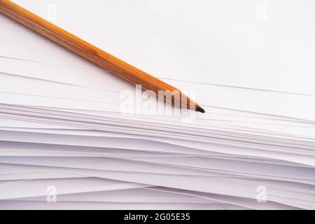 Un crayon repose sur une pile de feuilles de papier. Gros plan Banque D'Images