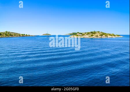 Côte Adriatique avec plage rocheuse, petites îles, bateaux et yachts à voile dans la mer bleue, Croatie, Dalmatie Banque D'Images