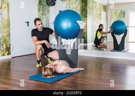 Entraîneur personnel aidant une femme à faire des exercices de pilates dans une salle de gym Banque D'Images