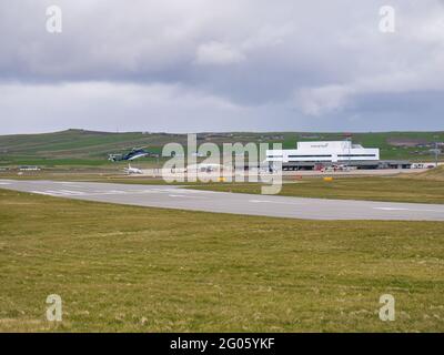 Par une journée nuageux et couvert, un hélicoptère atterrit à l'aéroport de Sumburgh, au sud de Shetland, au Royaume-Uni. Banque D'Images