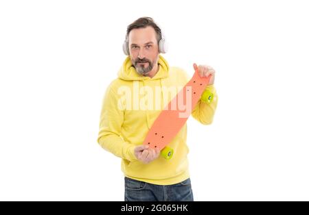 homme heureux écouter de la musique dans les écouteurs tenir penny skateboard isolé sur blanc, culture du skateboard. Banque D'Images