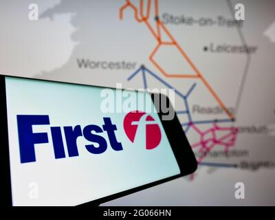 Smartphone avec le logo de la société de transport britannique FirstGroup plc sur l'écran en face du site Web des entreprises. Effectuez la mise au point au centre-droit de l'écran du téléphone. Banque D'Images