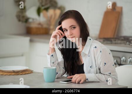 Jeune femme brune étudiante avec téléphone mobile. Réseaux sociaux, smartphones et gadgets modernes comme moyen de communication et d'activités de loisirs Banque D'Images