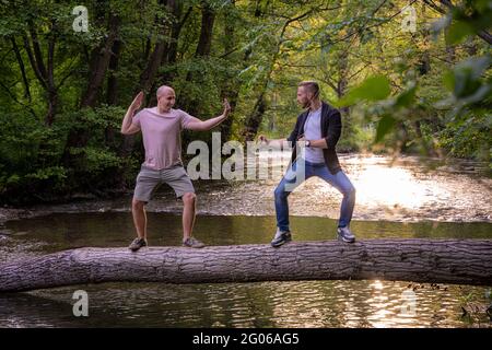 Deux gars jouent dans le style des arts martiaux sur un pont en rondins Banque D'Images