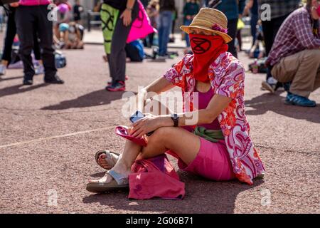 LONDRES, Royaume-Uni - l'activiste de la rébellion de l'extinction est assis sur le trottoir portant des vêtements colorés et un visage couvrant lors d'une manifestation contre le changement climatique Banque D'Images