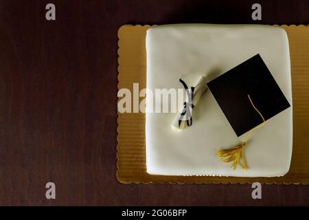 Gâteau blanc de remise de diplôme avec chapeau sur le dessus et décor de diplôme. Vue de dessus. Banque D'Images