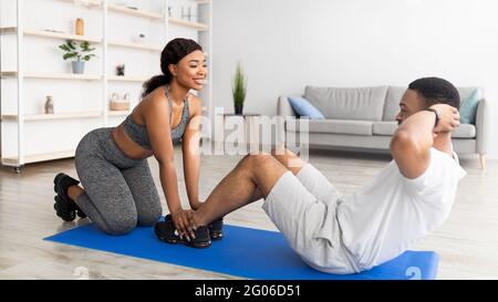 Cool noir gars faisant des exercices de noyau avec sa petite amie, l'entraînement comme équipe à l'intérieur, panorama Banque D'Images