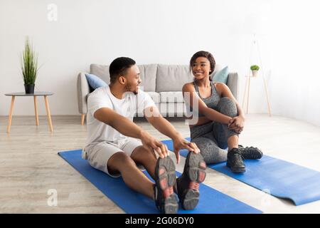 Couple noir sportif faisant des exercices sur les tapis de sport à la maison, sur toute la longueur. Concept de vie saine Banque D'Images