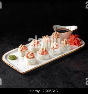 Roulé au saumon. Rouler avec du fromage caillé, du concombre, de l'avocat et du saumon au four avec du caviar tobiko sur fond noir. Menu sushi. Japonais foo Banque D'Images