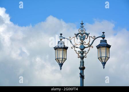 Lampadaire métallique de style ancien contre un ciel bleu avec des nuages blancs moelleux. THS est sur le front de mer à Portsmouth, en Angleterre, et porte le logo de la ville. Banque D'Images