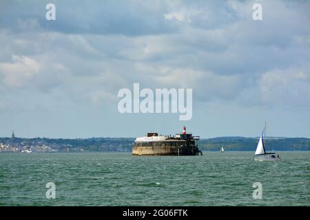 fort de Spitbank dans le Solent avec Ryde sur l'île de Wight au loin et un petit yacht sur une journée sinueuse dans le sud de l'Angleterre. Banque D'Images