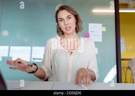 Femme d'affaires caucasienne souriante assise, ayant un appel vidéo d'affaires au travail Banque D'Images