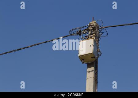 Boîte de transformateur de distribution et ligne électrique sur poteau en béton Banque D'Images