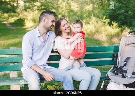 Bonnes vacances en famille. Jeunes parents. Caucasien souriant rire mère et père avec bébé fille dans le parc. Bonne famille maman, papa et fille Banque D'Images