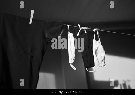 Prise de vue en niveaux de gris du linge et des masques suspendus sur une ligne Banque D'Images