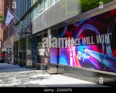 Le slogan « Science will win » se trouve dans la fenêtre des bureaux du siège mondial de Pfizer au 235 E 42nd Street, New York, NY, avec le drapeau de Pfizer avec le trottoir de NYC et les fronts d’achats alors que les États-Unis font des progrès de la vaccination contre les covids. Banque D'Images