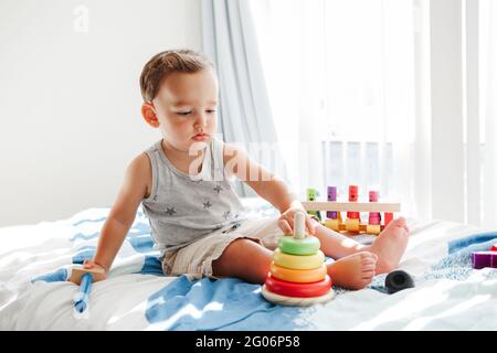 Bébé tout-petit mignon jouant avec l'apprentissage jouet pyramide blocs d'empilage à la maison. Formation de Montessori jeune âge. Activité de développement amusante main-cerveau pour enfants Banque D'Images