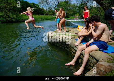 Une femme saute dans l'eau tandis que les gens apprécient le temps chaud à Warleigh Weir, Bath, le premier jour de l'été météorologique. Date de la photo: Mardi 1er juin 2021. Banque D'Images