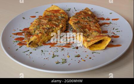 Omelette au bacon recouverte de sauce chaude et saupoudrée de ciboulette séchée et de poivre moulu Banque D'Images