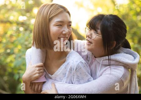 Portrait d'une femme asiatique souriante avec sa fille embrassant dans le jardin Banque D'Images