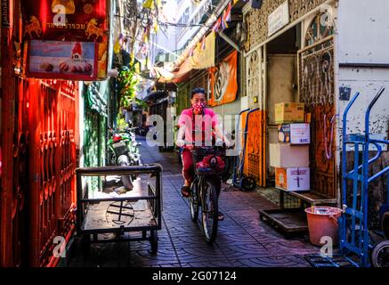 Une cycliste se promènait dans une allée colorée dans le quartier chinois de Bangkok, en Thaïlande Banque D'Images