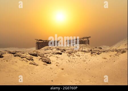 Petites cabanes au milieu du désert avec un paysage étonnant. Cabane en pierre du désert sous le soleil brûlant. Coucher de soleil dans le désert Banque D'Images