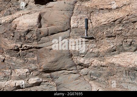 Digue basaltique à marges refroidies qui pénètre dans la roche métamorphique (gneiss), Californie du Sud-est. Marteau perforateur pour balance. Banque D'Images