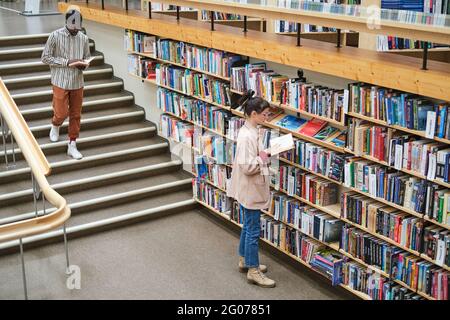 Les jeunes choisissent des livres et les lisent dans la bibliothèque Banque D'Images