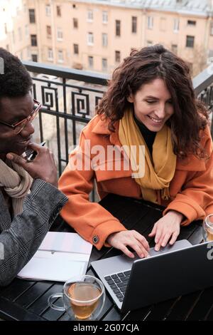 Un couple d'affaires assis à la table et travaillant sur un ordinateur portable tout en étant assis dans un café extérieur Banque D'Images