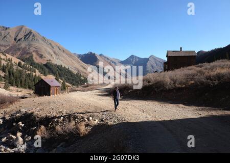 Un homme marche sur une route de terre à travers la ville minière abandonnée d'Animas Forks, Colorado, États-Unis Banque D'Images