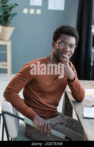 Portrait d'un jeune homme d'affaires africain souriant à la caméra tout en travaillant au bureau Banque D'Images