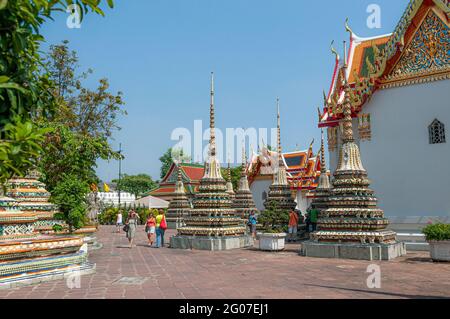 Touristes marchant autour de prangs colorés ornés dans le temple bouddhiste Wat Pho Wat po à Bangkok en Thaïlande en Asie du Sud-est. Banque D'Images