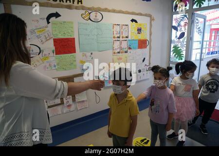 Ankara, Turquie. 1er juin 2021. Un enseignant mesure la température des enfants dans un jardin d'enfants à Ankara, Turquie, le 1er juin 2021. La Turquie est entrée dans une nouvelle phase mardi dans la lutte contre le COVID-19 après que le gouvernement ait encore assoupli les restrictions anti-coronavirus. Le verrouillage du week-end a été levé le samedi, et les couvre-feux nocturnes en semaine ont été reportés d'une heure. Les restaurants, les cafés et les installations sportives sont également devenus opérationnels avec un nombre limité de clients. Crédit: Mustafa Kaya/Xinhua/Alamy Live News Banque D'Images